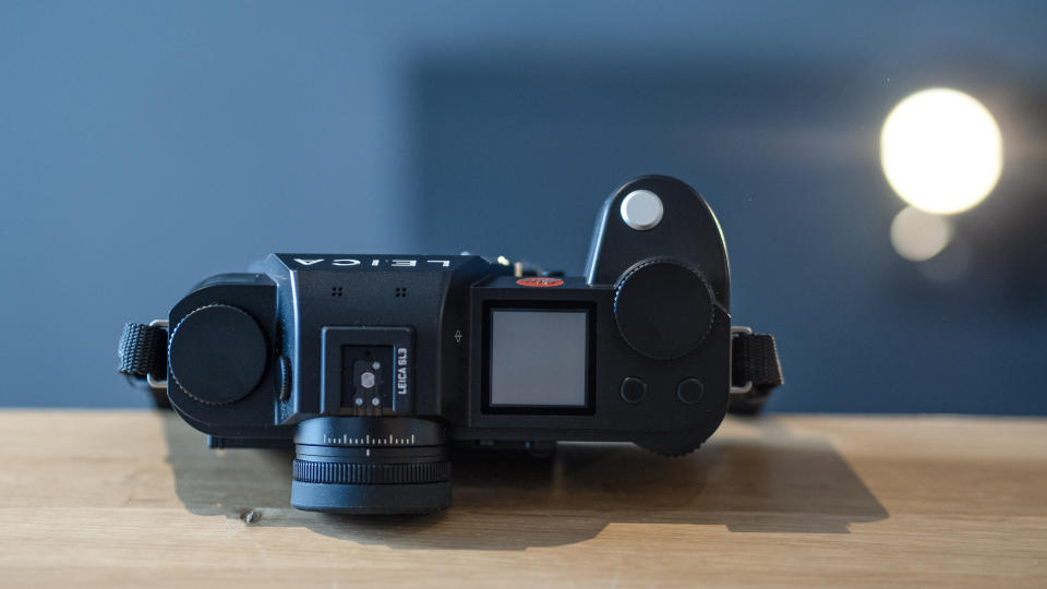 Leica SL3 camera on a wooden surface against a blue background