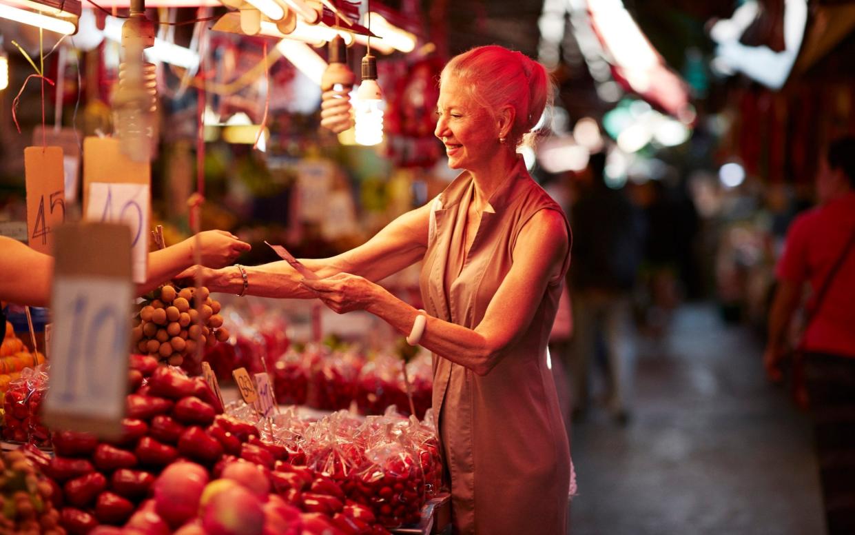 Smiling woman paying for langsat fruit while standing at market stall