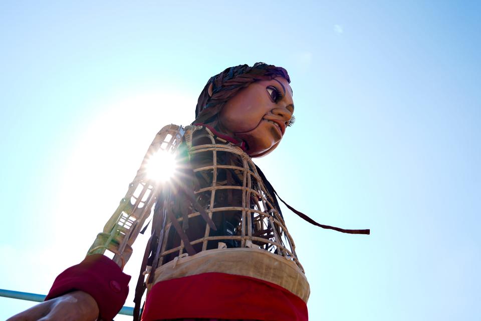 Light shines through the torso of Little Amal as she makes her way across the Roebling Bridge to Cincinnati on Friday, Sept. 22, 2023.