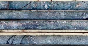 Photograph of drill core at 150 m in drill hole HK22-014.  Nearly complete replacement of alkaline shonkinite host rock by potassic, fenite alteration consisting of magnetite-biotite-calcite-amphibole which is most intense around phoscorite (carbonatite) veins with semi-massive magnetite-apatite. Hydrothermal-magmatic shatter breccia and quench textures are evident.  Similar hydrothermal vein, breccia, replacement and alteration textures, together with fluorite, are evident in intervals from tens to hundreds of metres long in all eight drill holes completed in the third drill program at Hecla-Kilmer in April-May 2022.