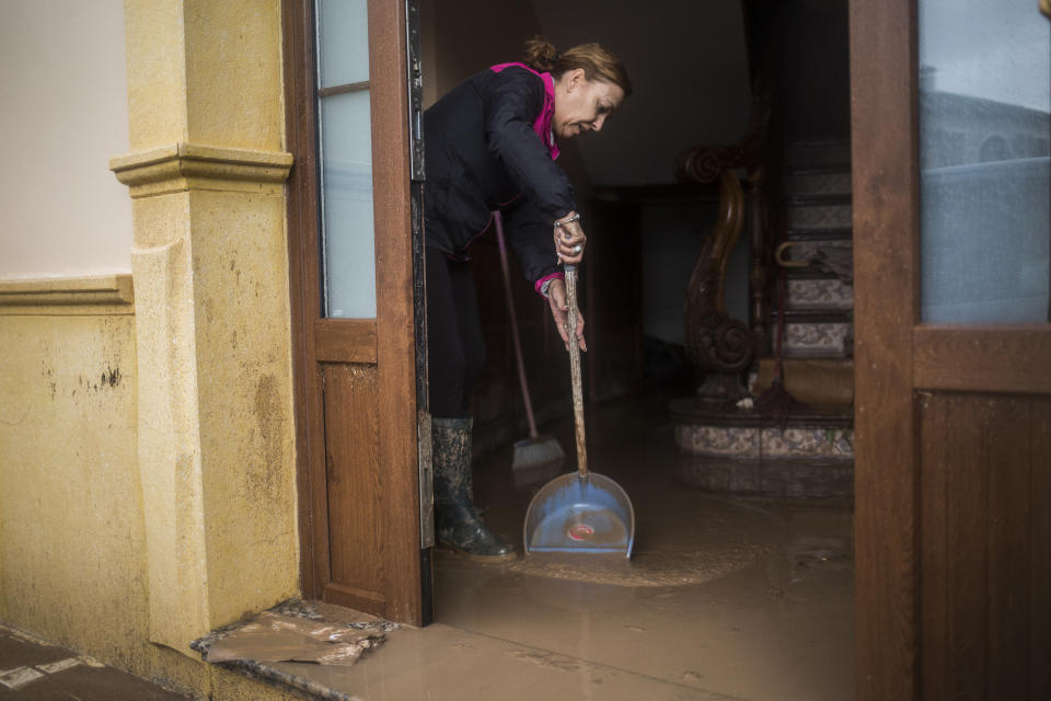 A woman cleans her house after heavy rain in the village of Campillos, Spain, where heavy rain and floods have caused severe damage and the death of a firefighter according to Spanish authorities Sunday, Oct. 21 2018. Emergency services for the southern region of Andalusia say that the firefighter went missing when his truck overturned on a flooded road during heavy rains that fell through the night, and his body was found after a search Sunday morning. (AP Photo/Javier Fergo)