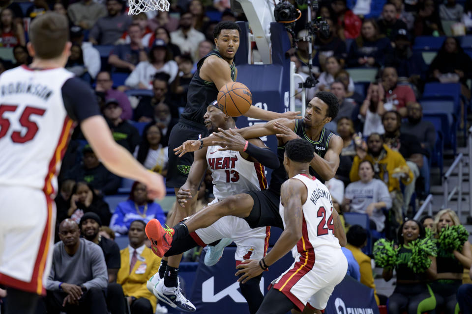 New Orleans Pelicans guard Trey Murphy III, center top, and forward Herbert Jones, right top, battle Miami Heat center Bam Adebayo (13) for a rebound during the first half of an NBA basketball game in New Orleans, Friday, Feb. 23, 2024. (AP Photo/Matthew Hinton)