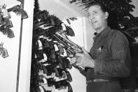 FILE - In this Aug. 13, 1958, file photo, selecting a pair of six-guns from the Hollywood studio's gun department, Rodd Redwing checks the feel of the weapons in Los Angeles. An actor and a gun expert, Redwing instructs other actors in fast gun drawing and six-gun shooting. (AP Photo/David F. Smith, File)