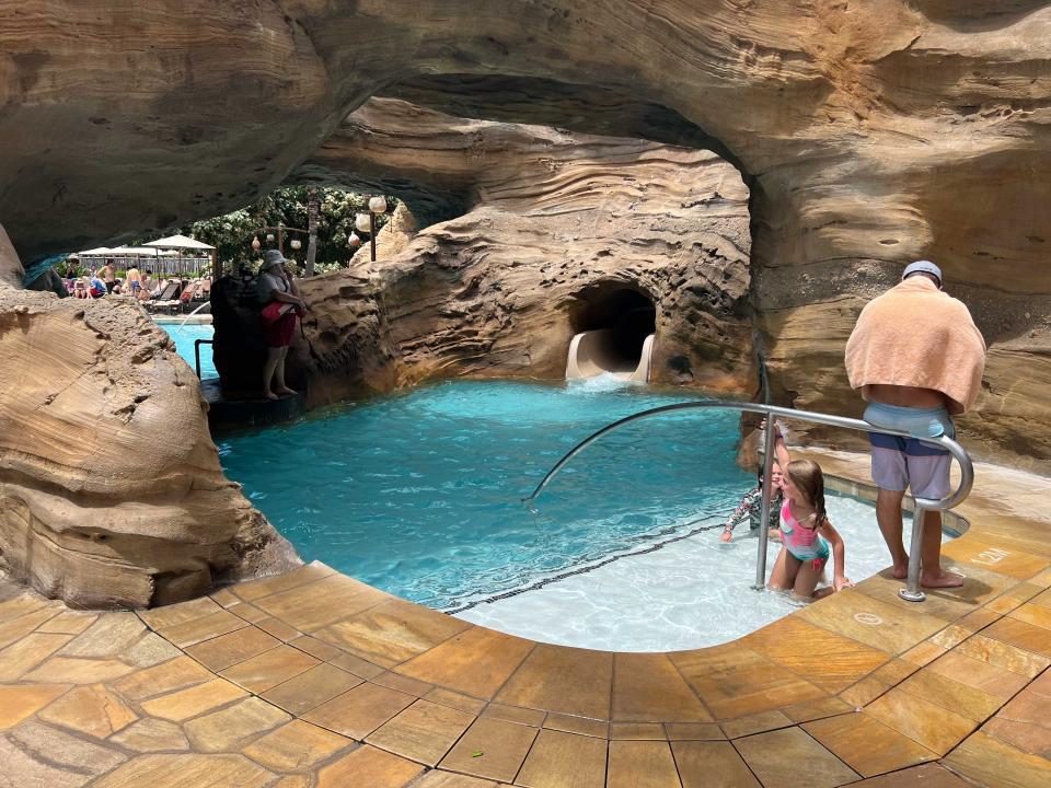 A water slide leading into a small pool area in a cave like area.