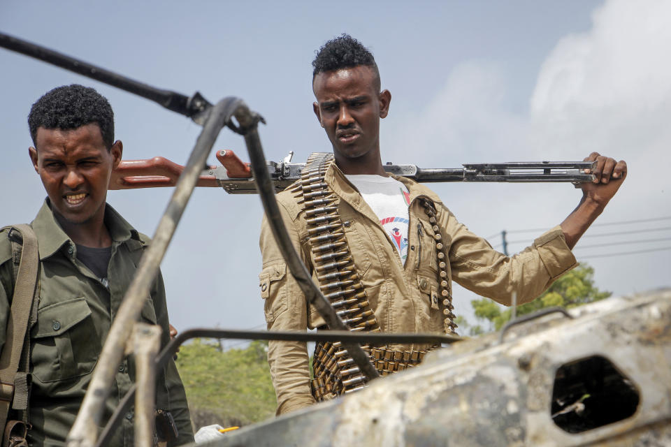 Security forces look at the wreckage after a suicide car bomb attack that targeted the city's police commissioner in Mogadishu, Somalia Saturday, July 10, 2021. At least nine people are dead and others wounded after the large explosion, a health official at the Medina hospital said, noting that the toll reflected only the dead and wounded brought there. (AP Photo/Farah Abdi Warsameh)