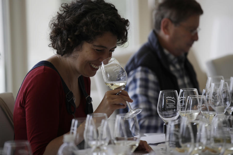 In this image taken on Monday, Oct. 15, 2018, an expert wine tester smiles as she tastes a glass of Prosecco during a wine testing in Asolo, Italy. Prosecco has become the best-selling sparkling wine in the world, and experts say it is eroding the more casual corner of champagne's market while aiming higher. Its production eclipsed champagne's five years ago and is now 75 percent higher at 544,000 bottles three-quarters of which for export. (AP Photo/Luca Bruno)
