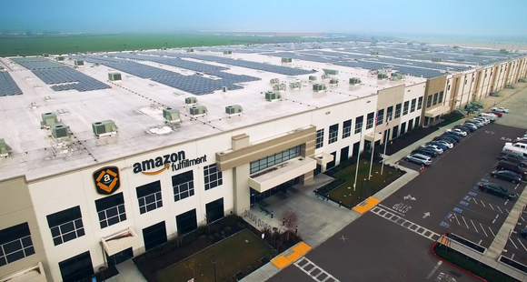 A bird's eye view of an Amazon warehouse sporting solar panels on the roof.