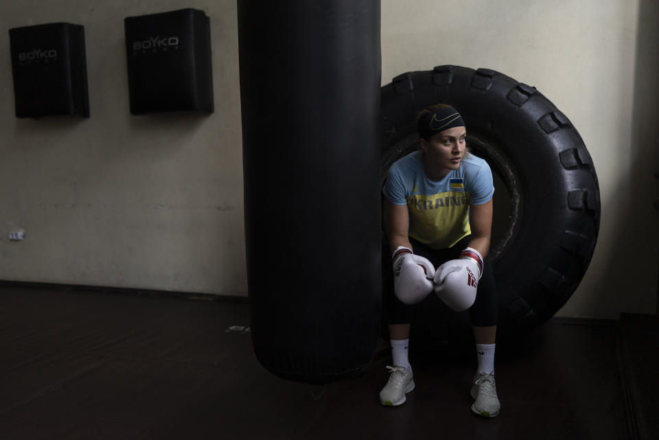 Ukrainian boxer Anna Lysenko sits on a tire while taking a short break during training at Kiko Boxing Club in Kyiv, Ukraine, Tuesday, July 11, 2023. Lysenko dedicates long hours preparing for next year's Paris Olympics despite the unsettling sounds of explosions booming outside. (AP Photo/Jae C. Hong)