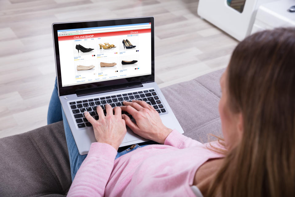 Close-up Of Woman Sitting On Sofa Shopping Footwear's Online On Laptop At Home