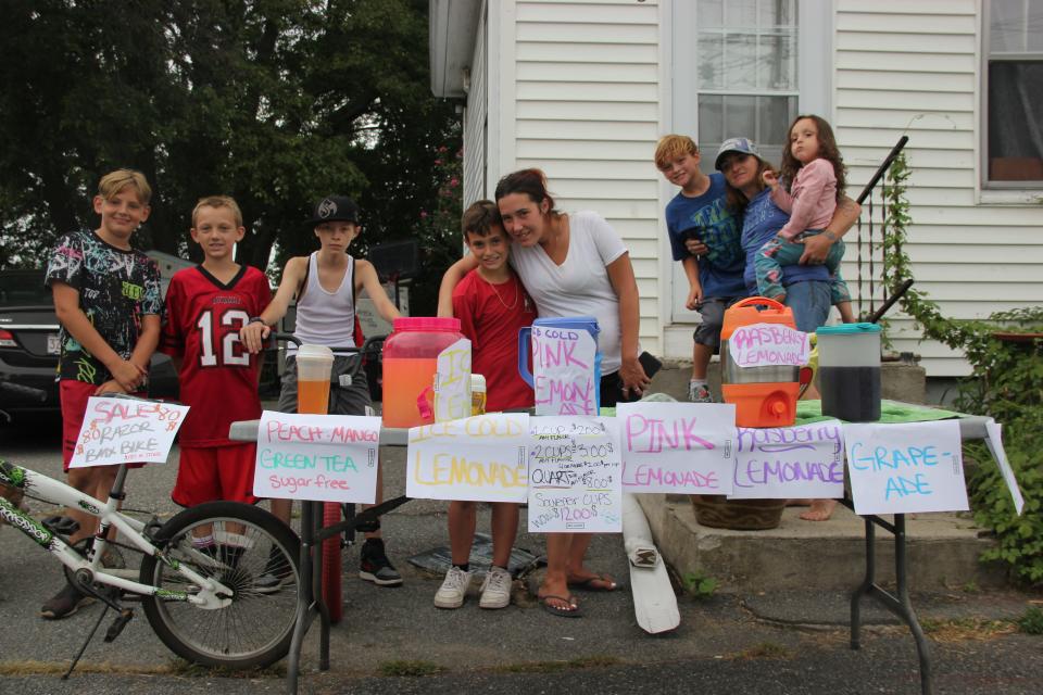 Residents of Swansea's Ocean Grove neighborhood including Alyssa Lafferty, second from right, work a homemade lemonade stand, near Pleasure Island.