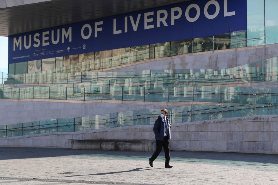 A man wearing a face mask walks past the Museum of Liverpool (PA)