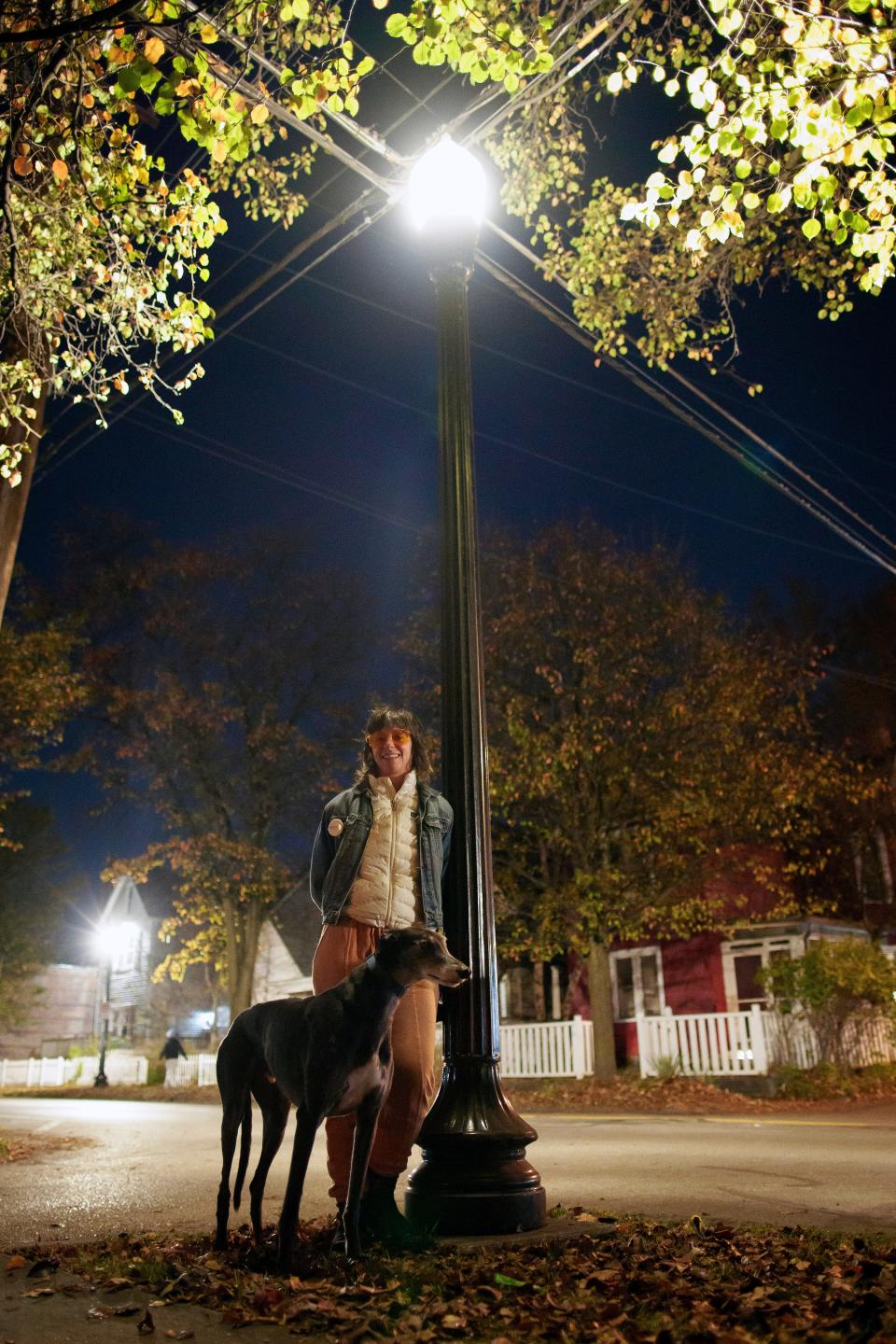 Heidi Vanderpool walks her dog, Moose, past new street lamps installed along Third Avenue in Columbus, Ohio, in November 2022. Vanderpool worries about the light pollution caused by the brighter LEDs.