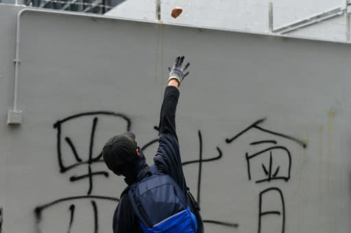 A protester throws a rock at a police station in the Tseung Kwan O district of Hong Kong