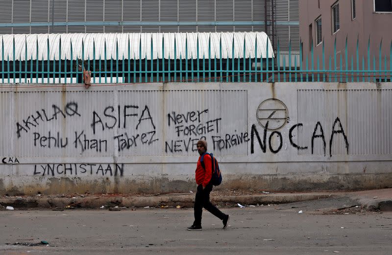 A man walks past a graffiti during a protest against a new citizenship law, in New Delhi