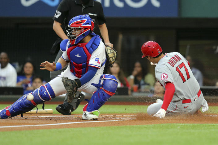 Texas Rangers catcher Jose Trevino, left, gets the ball late as Los Angeles Angels starting pitcher Shohei Ohtani, right, scores in the first inning during a baseball game on Monday, April 26, 2021, in Arlington, Texas. (AP Photo/Richard W. Rodriguez)