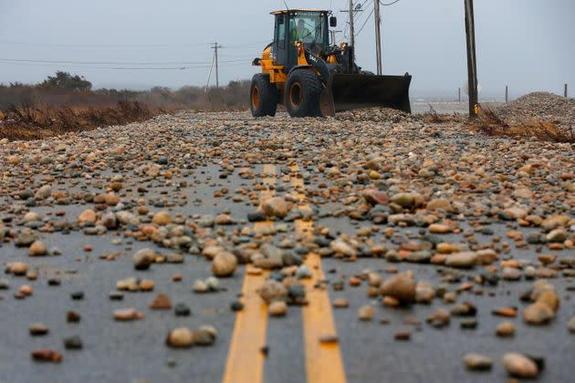 In Westport, Massachusetts, on Friday, a truck clears piles of stones blown ashore by a storm surge.