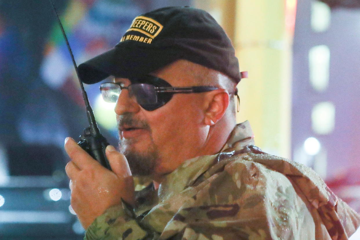 Oath Keepers founder Stewart Rhodes, dressed in camouflage, uses a walkie-talkie as he departs from a Trump rally.