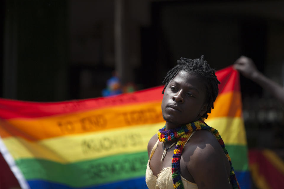 A transgender Ugandan poses in front of a rainbow flag during the 3rd Annual Lesbian, Gay, Bisexual and Transgender (LGBT) Pride celebrations in Entebbe, Uganda, Saturday, Aug. 9, 2014.  Scores of Ugandan homosexuals and their supporters are holding a gay pride parade on a beach in the lakeside town of Entebbe. The parade is their first public event since a Ugandan court invalidated an anti-gay law that was widely condemned by some Western governments and rights watchdogs. (AP Photo/Rebecca Vassie)