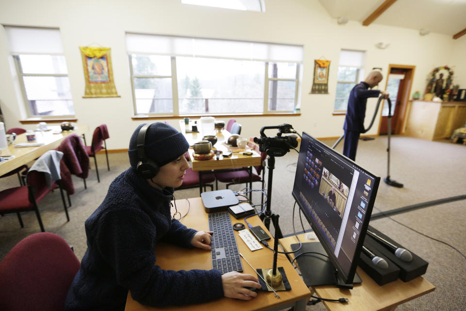 Lay person in training Munsel Cohn, left, edits video as fellow lay person in training Stephen Cohn, left, vacuums in the dining hall at Sravasti Abbey, a Buddhist monastery, Thursday, Nov. 18, 2021, in Newport, Wash. (AP Photo/Young Kwak)