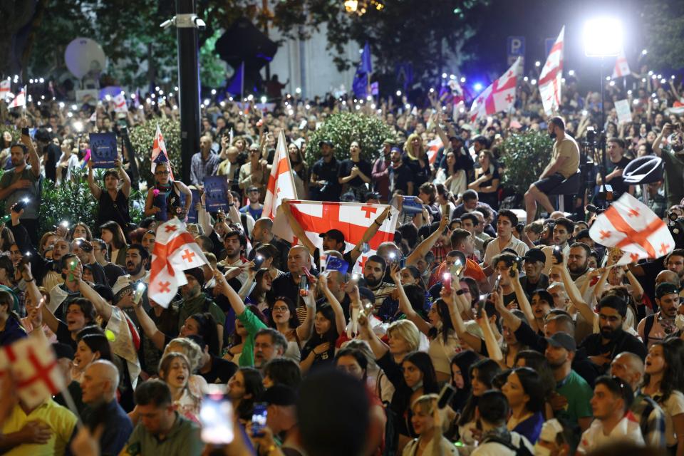 Des manifestants brandissant des drapeaux de la Géorgie alors qu’ils protestent devant le Parlement lors d’un rassemblement contre un projet de loi controversé sur « l’influence étrangère », qui, selon Bruxelles, porterait atteinte aux aspirations européennes du pays, à Tbilissi, le 1er mai 2024.