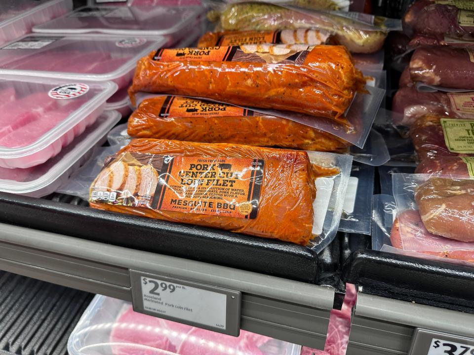 A package of pork loin with an orange marinade and label on a shelf at Aldi