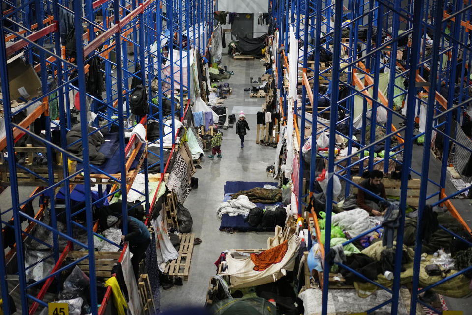 FILE - Migrants settle at a logistics center at the checkpoint logistics center "Bruzgi" at the Belarus-Poland border near Grodno, Belarus, Dec. 22, 2021. A year after migrants started crossing into the European Union from Belarus to Poland, Polish authorities are planning to announce Thursday that a 5.5-meter-tall steel wall along its border to the north with Belarus is set to be completed. The purpose of the wall is to keep out asylum seekers fleeing conflict and poverty in the Middle East and Africa. (AP Photo/Pavel Golovkin, File)