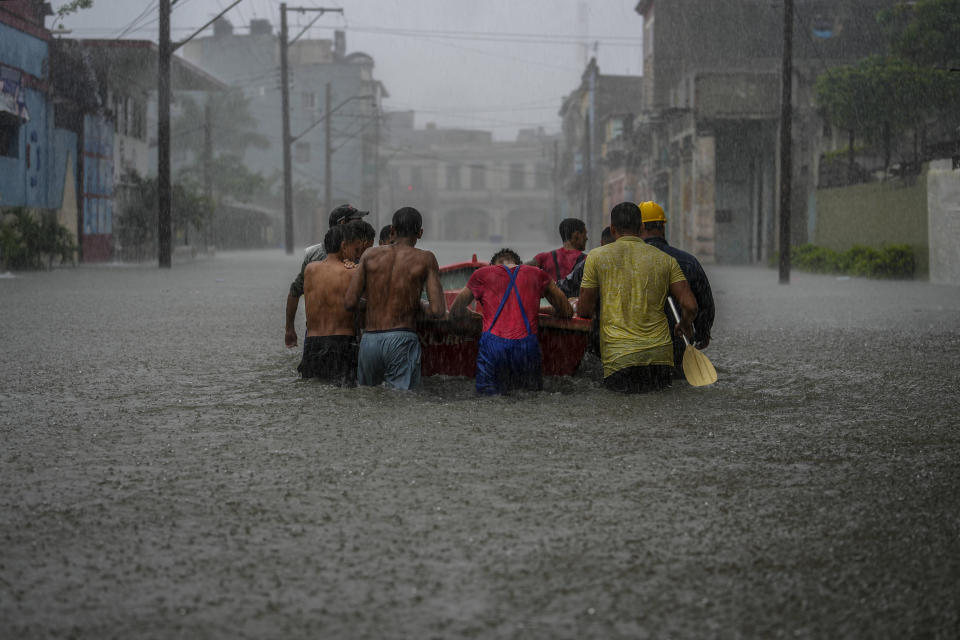 Los residentes empujan un bote a través de una calle inundada para rescatar a un vecino que no pudo salir de su casa durante un ciclón tropical en La Habana, Cuba, el viernes 3 de junio de 2022. (AP Foto/Ramón Espinosa)