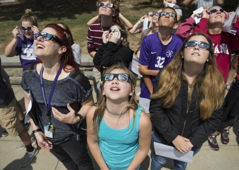 Yverre Berzins, 11, center, and her mother Angela Berzins, left, watch the partial solar eclipse together on Aug. 21, 2017, at Bloomington High School South.