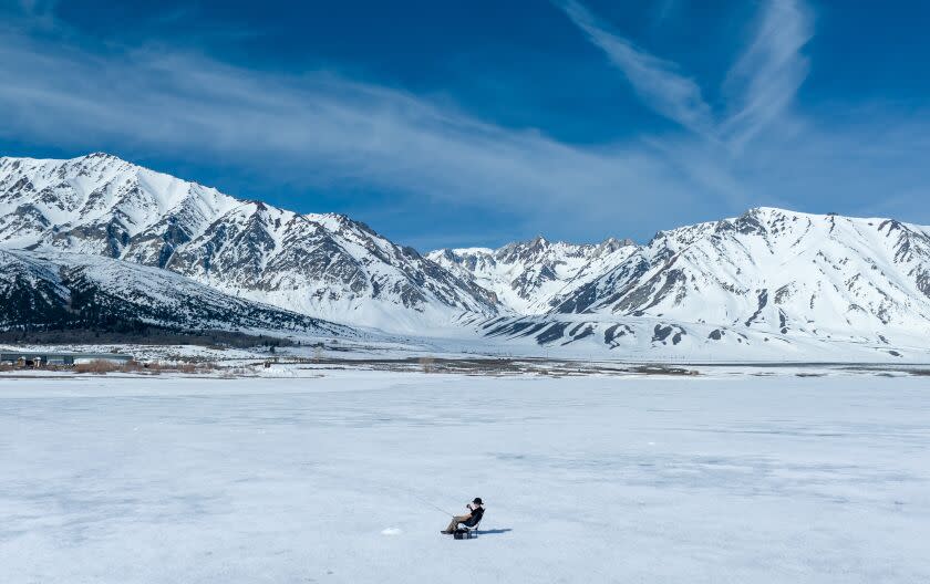 CROWLEY LAKE, CA - April 29: An ice fisherman waits for a bite as his line is dropped into a hole in a frozen Crowley Lake on the official opening day of Eastern Sierra trout season Saturday, April 29, 2023 in Crowley Lake, CA. Ice fishing was the only option on the lake as the marina was still frozen. (Brian van der Brug / Los Angeles Times)