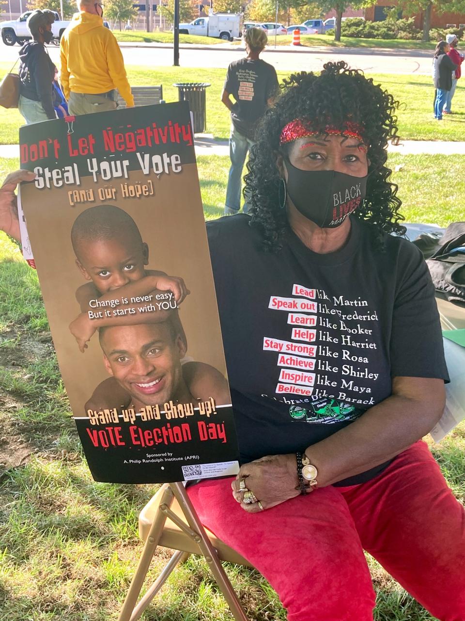 In this 2020 photo, Deboraha Sallee holds a poster from the A. Philip Randolph Institute that encourages people to vote in the November election. It says 'Don't Let Negativity Steal your vote (and our hope.)'