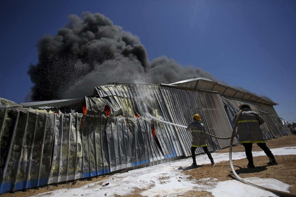 Palestinian firefighters work to extinguish a fire at a paint factory after it was hit by an Israeli airstrike, in Rafah, Gaza Strip, Tuesday, May 18, 2021. (AP Photo/Yousef Masoud)