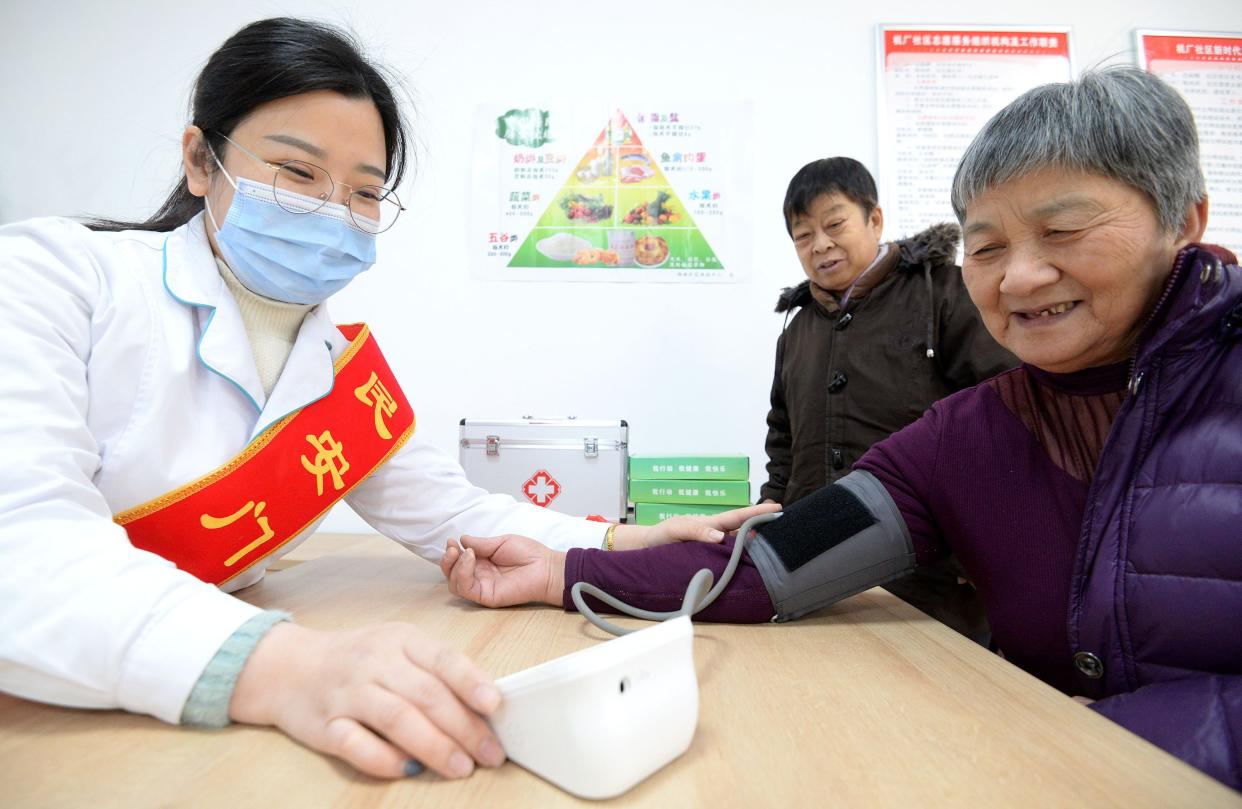 A medical volunteer at a community home Care center for the aged takes blood pressure measurements free of charge in Handan, North China's Hebei Province, Dec. 16, 2020.