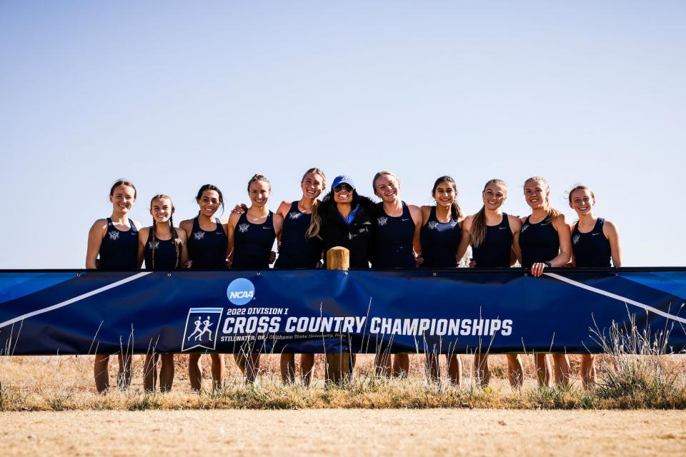 BYU women’s cross-country coach Diljeet Taylor, center, poses with members of the BYU women’s team in Stillwater, Oklahoma, at the NCAA champsionships. | BYU Photo