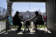 Amanda Burkhead and Josh Cupit play a card game while sitting on the front porch, Thursday, April 2, 2020, in Greensburg, Ind. The couple worked at Honda will the plant was shut down due to COVID-19. Three southeast Indiana counties have among the highest per-capita coronavirus infection rates in the country. (AP Photo/Darron Cummings)