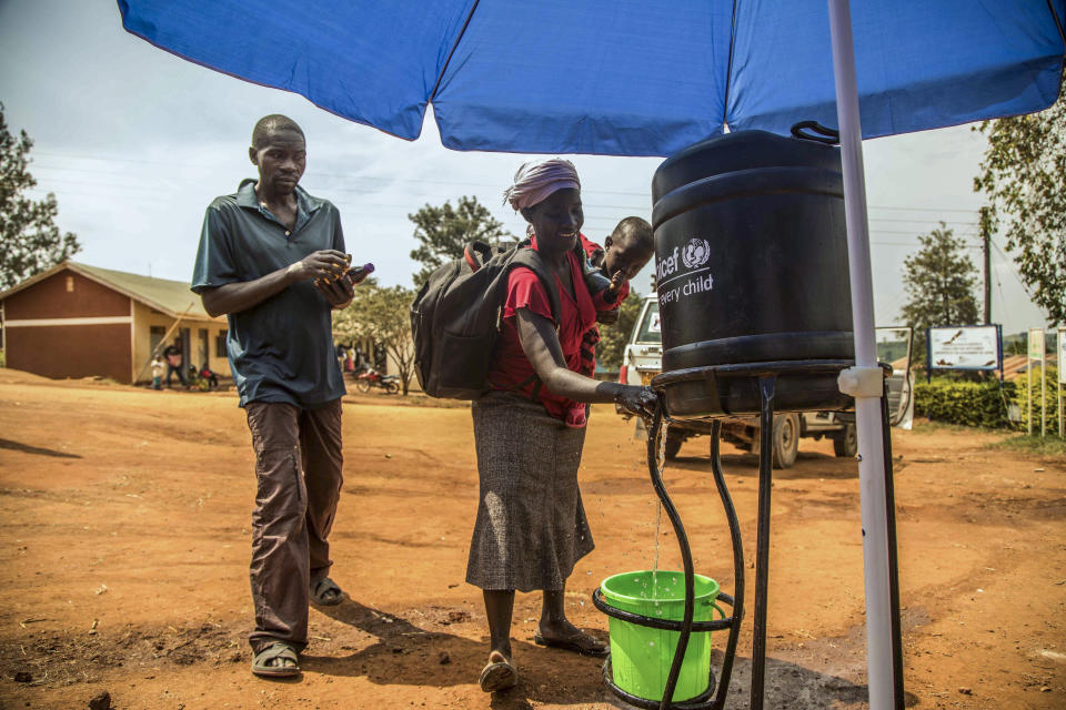 In this photo provided by the International Rescue Committee, Congolese refugees wash their hands before being screened for Ebola symptoms at the IRC triage facility in the Kyaka II refugee settlement in Kyegegwa District in western Uganda, Thursday, June 13, 2019. The Congolese pastor who is thought to have caused the Ebola outbreak's spread into Uganda was unknown to health officials before he died of the disease, the World Health Organization's emergencies chief said Thursday, underlining the problems in tracking the virus. (Kellie Ryan/International Rescue Committee via AP)
