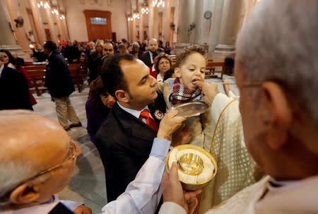 FILE PHOTO: A boy is carried by his father as he receives Holy Communion during a mass on Christmas Eve at Saint Joseph's Roman Catholic Church in Cairo, Egypt December 24, 2017. REUTERS/Amr Abdallah Dalsh/File Photo