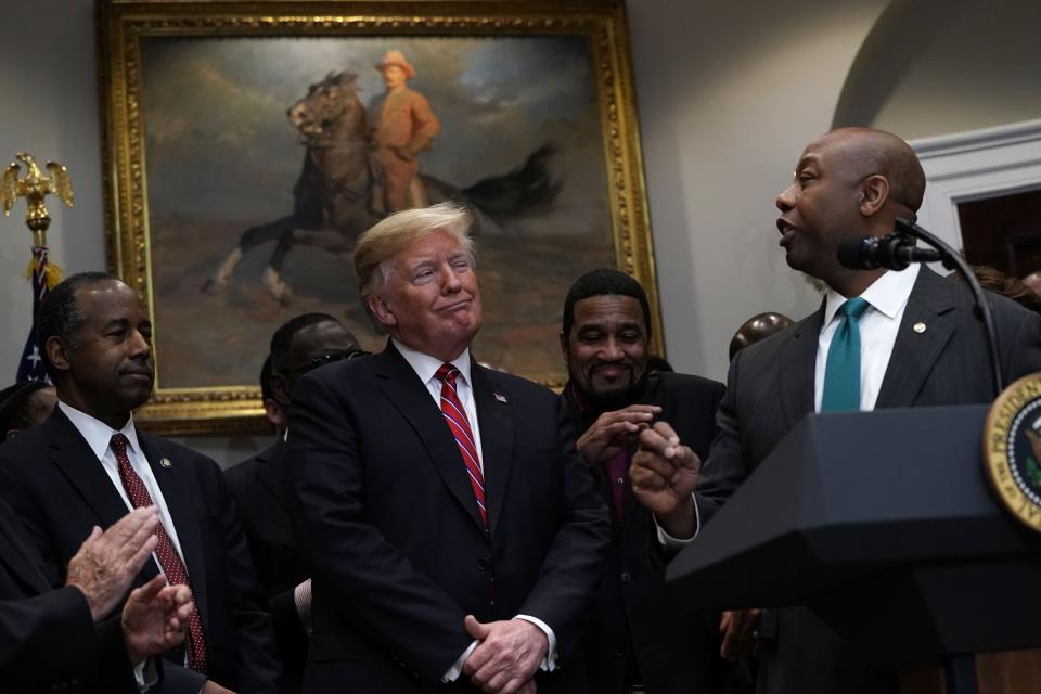 President Trump  reacts as Sen. Tim Scott, R-S.C., praises him as Secretary of Housing and Urban Development Secretary Ben Carson (L) looks on during a signing event of an executive order to establish the White House Opportunity and Revitalization Council on Dec. 12, 2018 at the Roosevelt Room of the White House in Washington.