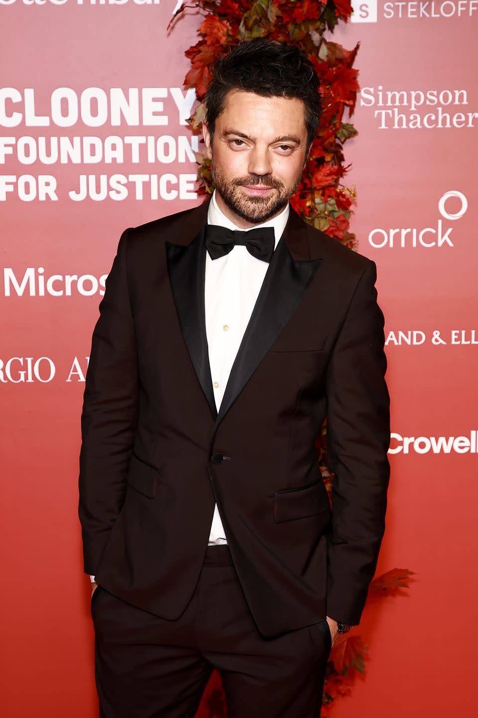 dominic cooper wears a black tuxedo and smiles for the camera