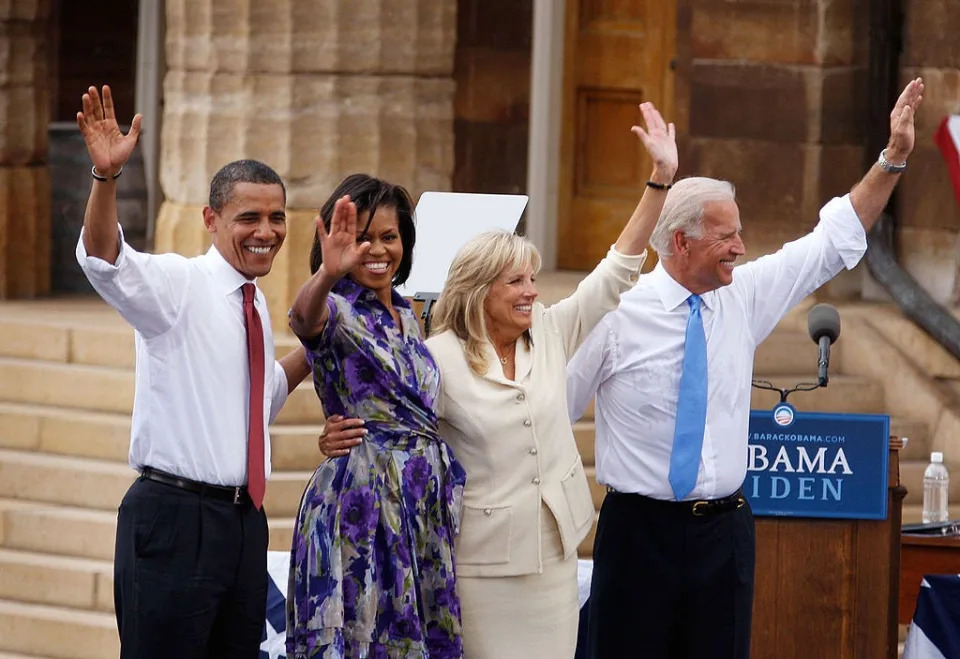 Barack Obama, Michelle Obama, Jill Biden, and Joe Biden wave at a crowd.