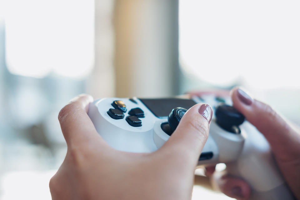 A woman holds a PlayStation controller.