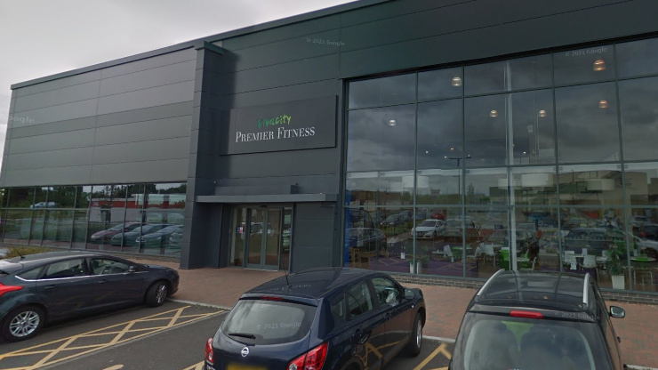 The exterior of Premier Fitness in Hampton, showing parked cars in front of a black cladded leisure centre building with large windows