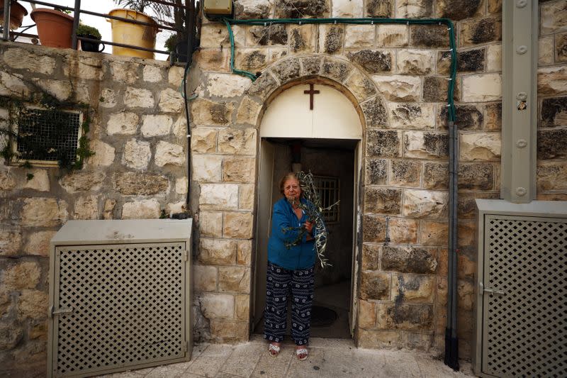 A woman holds an olive branch she received from members of the Latin Patriarchate which they distributed to Christian residents on Palm Sunday during Holy Week amid the coronavirus disease (COVID-19) outbreak, in Jerusalem's Old City