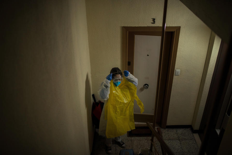 Home care nurse Alba Rodriguez puts on protective gear before visiting a patient in the Poble Sec neighborhood of Barcelona, Spain, March 30, 2020. A pediatric nurse by profession, Rodriguez has gotten creative to try to protect herself, fashioning hazmat suits out of giant yellow garbage bags that she and fellow nurses wear over their scrubs as extra protection. "We're like onions," she says of the extra layers. (AP Photo/Emilio Morenatti)