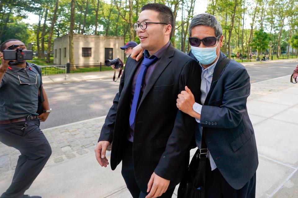 Zhu Yong, right, tries to shield himself from photographers as he leaves federal court, May 31, 2023, in the Brooklyn.