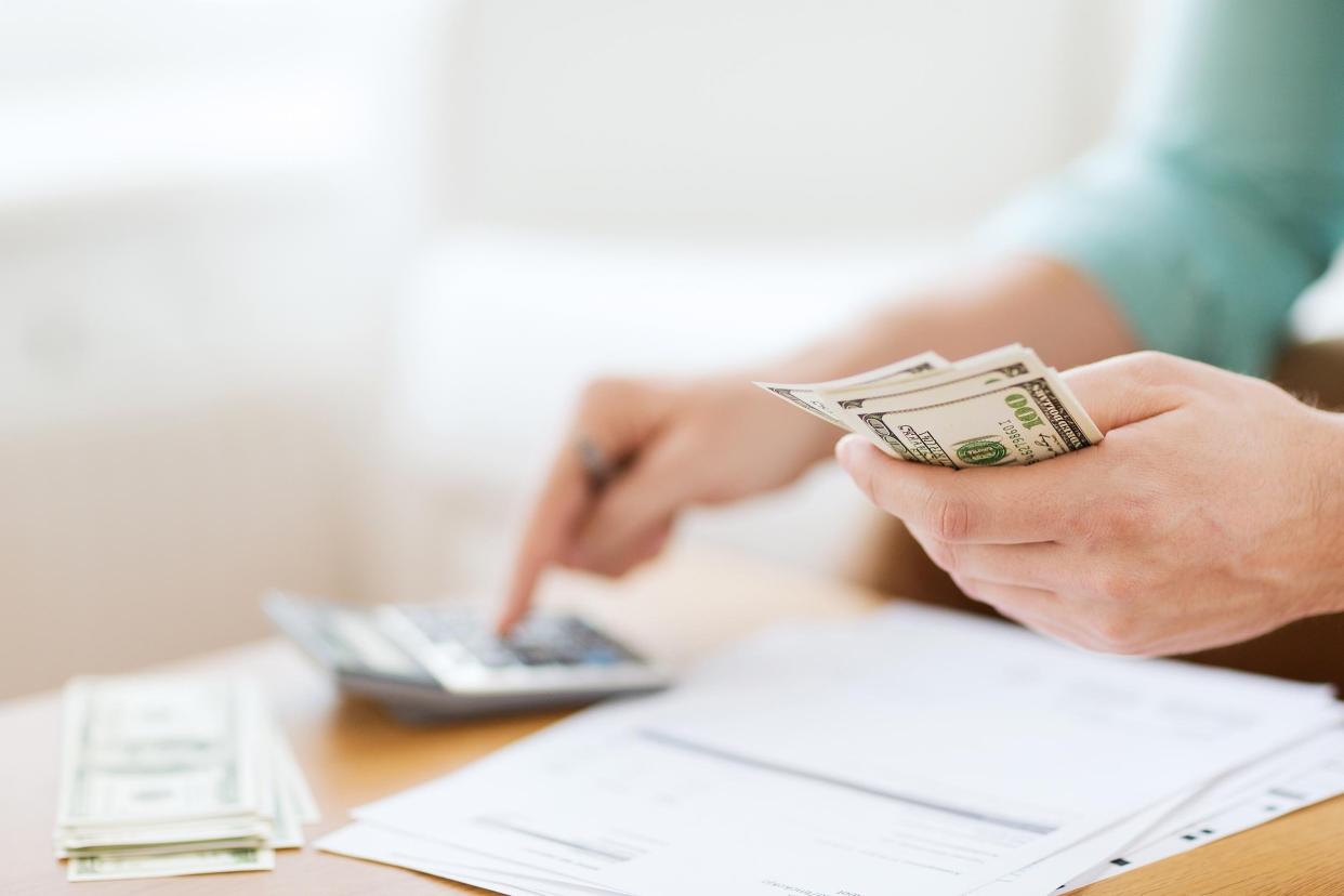 close up of man with calculator counting money and making notes at home