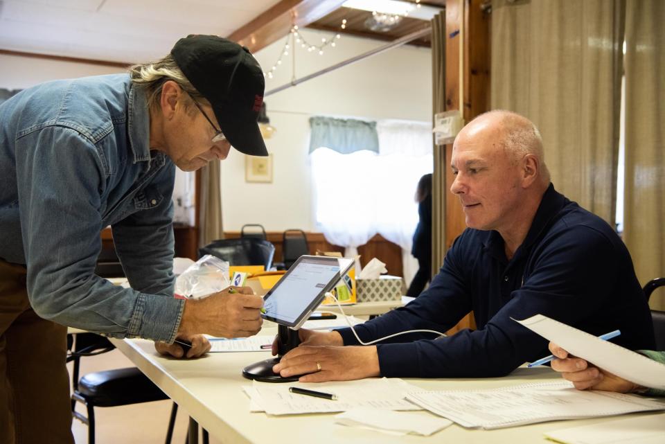 Steve Copper, right, minority inspector, helps check in voter, Richard Miller, inside the Plumseadville Firehouse in Plumstead Township on Tuesday, November 8, 2022.