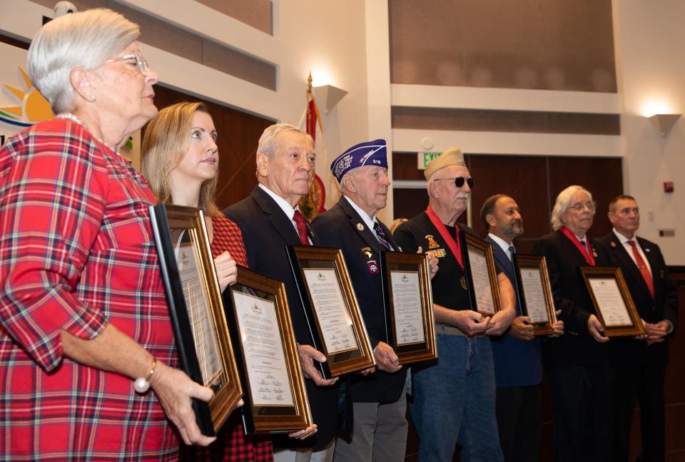 Carolyn Carroll, daughter of the late John Brinkley, and Meredith Hill, Brinkley's granddaughter, receive a recognition on his behalf alongside other honorees during a ceremony celebrating local veterans who are now part of the Florida Veterans Hall of Fame.