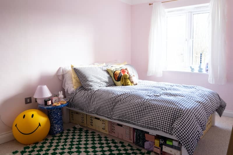 Items stored under bed in light pink room.