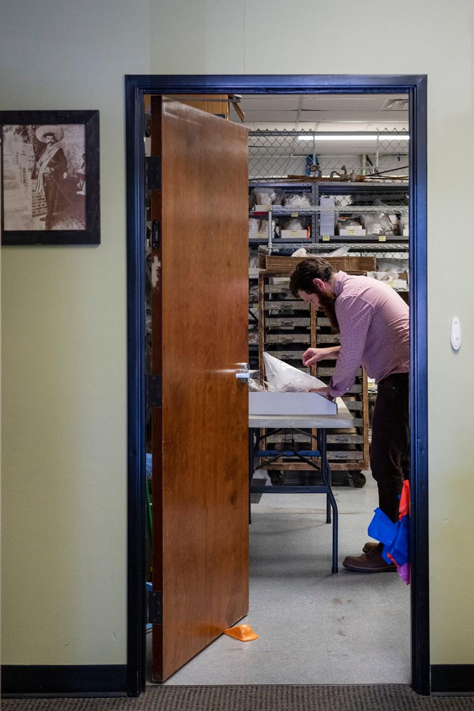 Archaeologist Alex Menaker looks at artifacts from Tom Cook's blacksmith shop at Stantec in Austin.