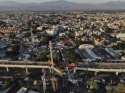 An aerial view of subway cars dangle at an angle from a collapsed elevated section of the metro, in Mexico City, Tuesday, May 4, 2021. The elevated section of Mexico City's metro collapsed late Monday killing at least 23 people and injuring at least 79, city officials said. (AP Photo/Fernando Llano)